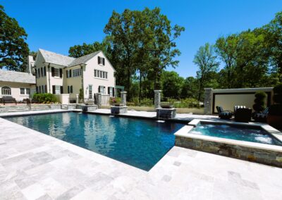 Design winning pool with hot tub and white tile. Three water features.
